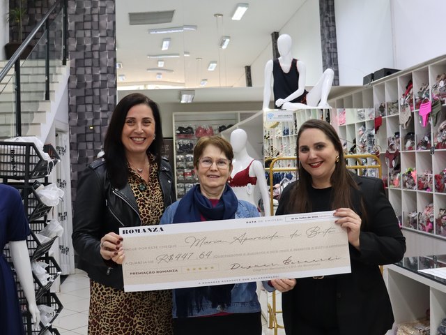 Maria Aparecida recebendo o cheque de premiação da Romanza